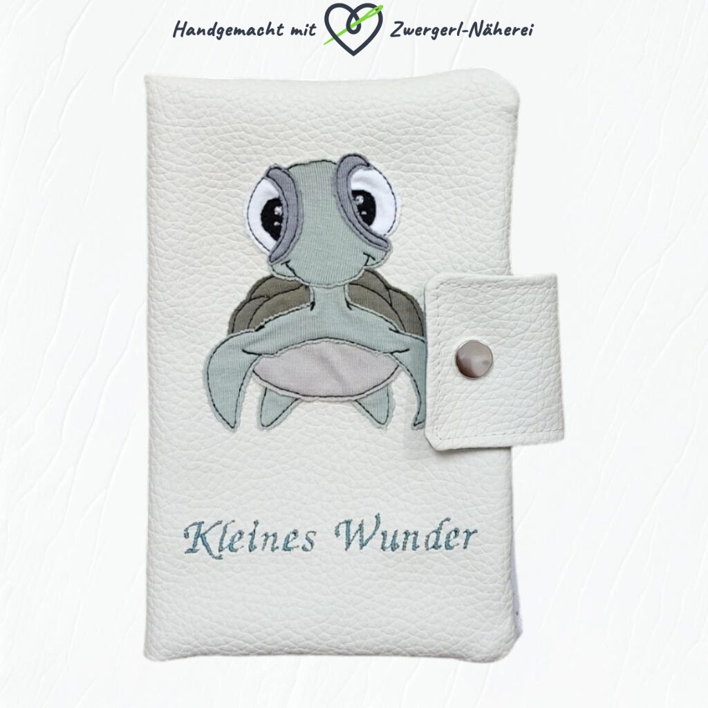 Mutterkindpass Hülle cremefarbenes Kunstleder mit eingestickter Schildkröten-Applikation und Spruch handmade Vorderansicht